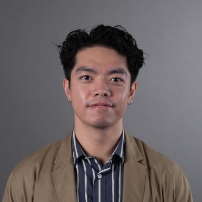 Yukai Chen smiling with brown jacket & blue striped shirt